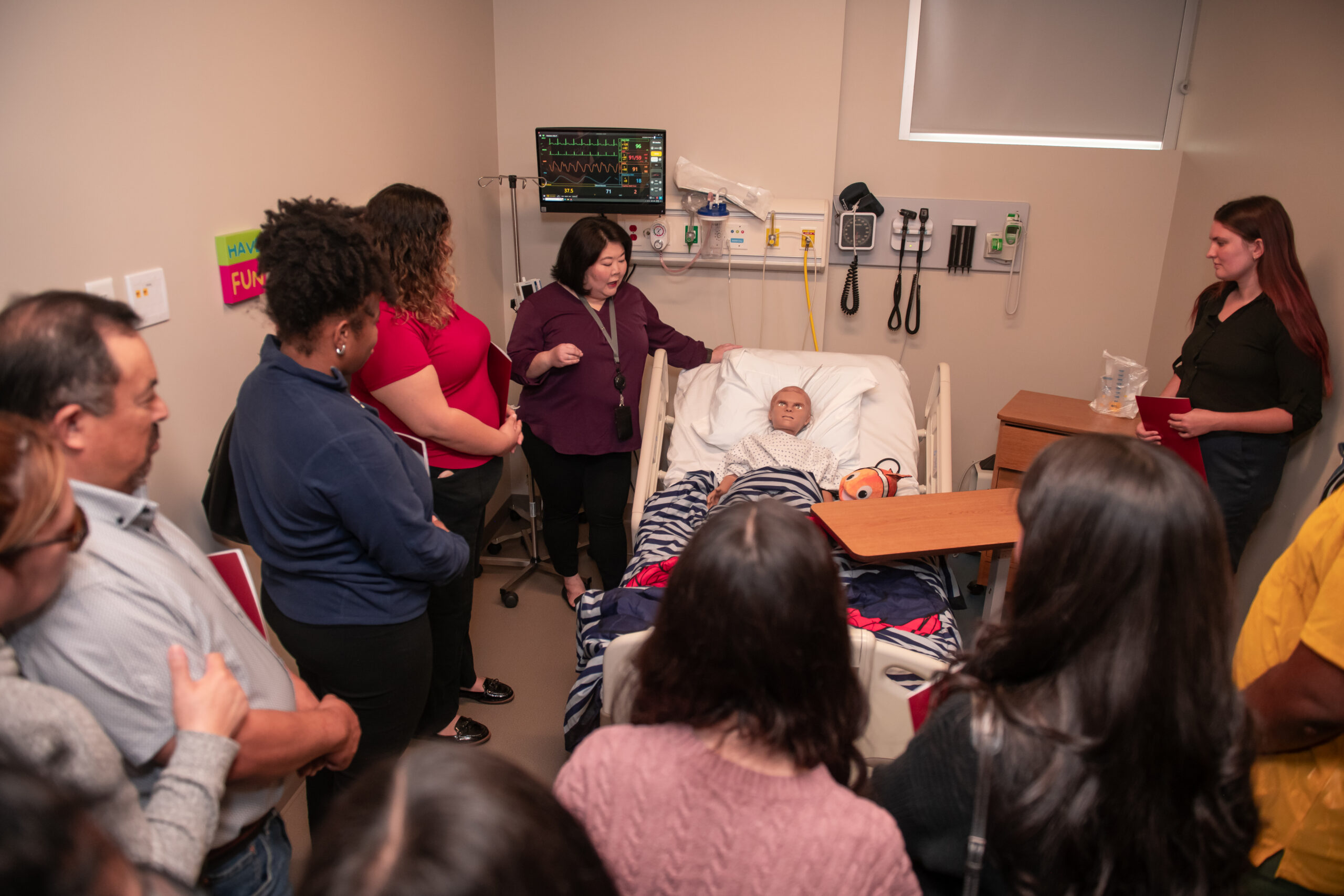 simulated hospital bed with child manikin and group around bed