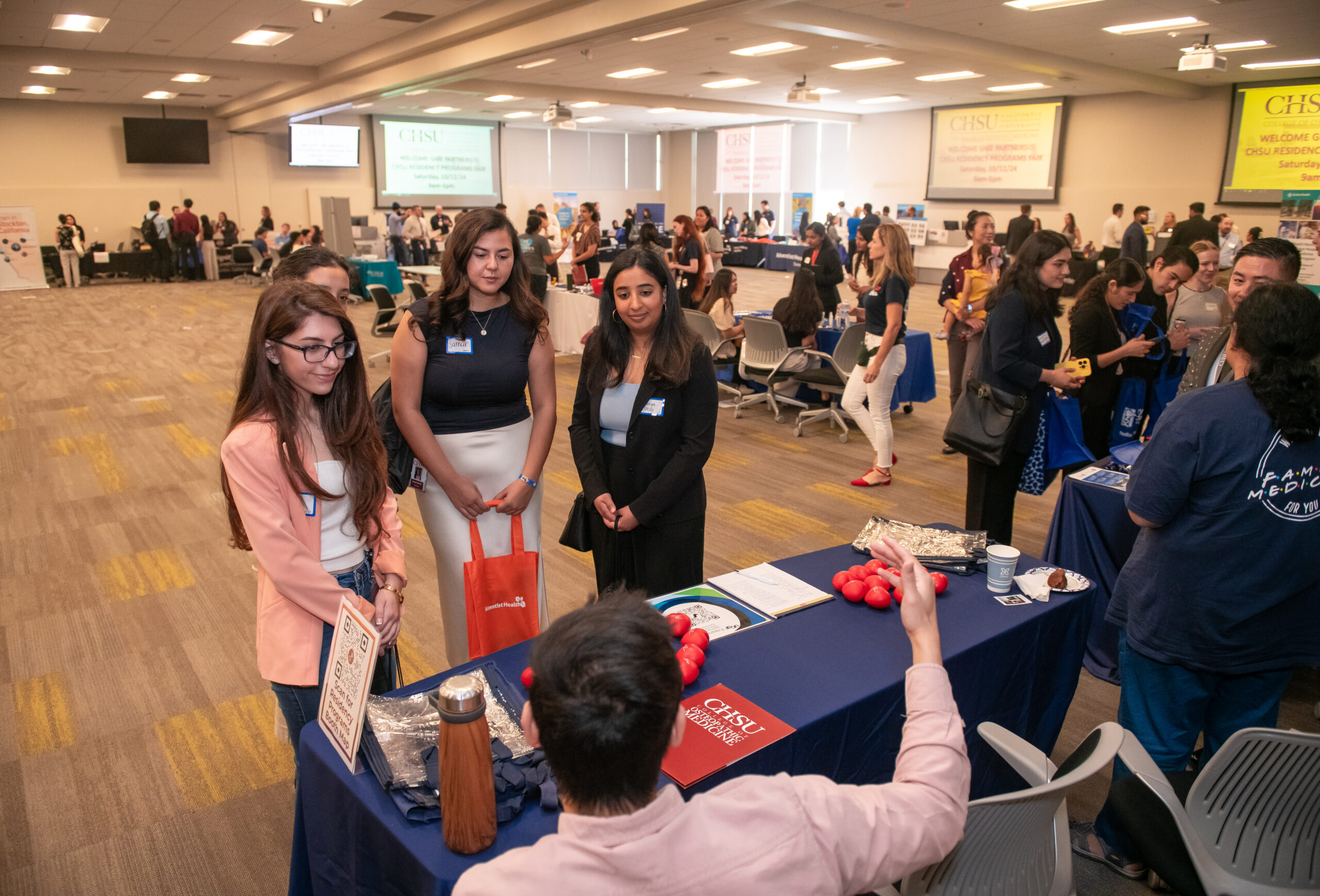 3 students talking to residency program at fair