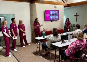 medical students in scrubs presenting to high school teachers seated at desks