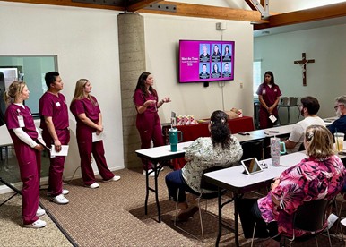 medical students in scrubs presenting to high school teachers seated at desks