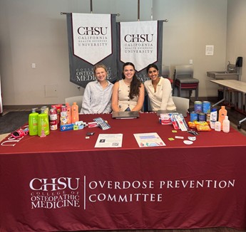 3 people sitting at table with red OPC cloth