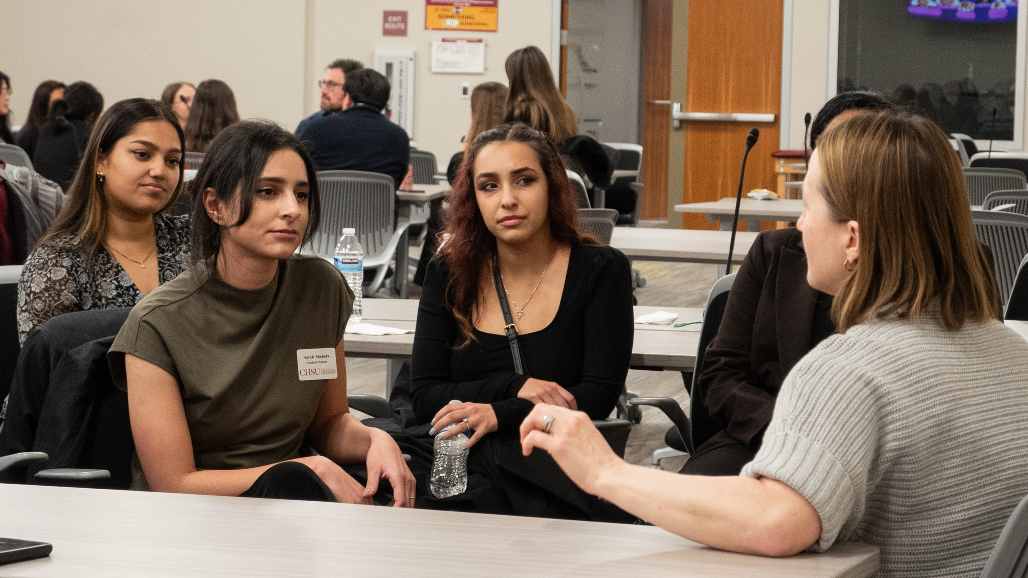 medical students listening to surgeon speak at table discussion