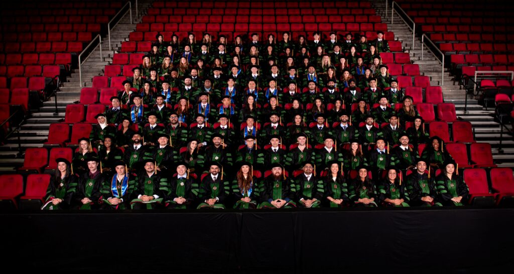 COM Class 2026 Group Photo in regalia, seated in stadium
