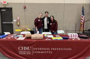 students standing behind Overdose Prevention Committee table with supplies on it