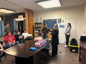 two students standing and guiding naloxone administration to seated students