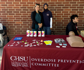 two medical students at Overdose Prevention Committee table with supplies