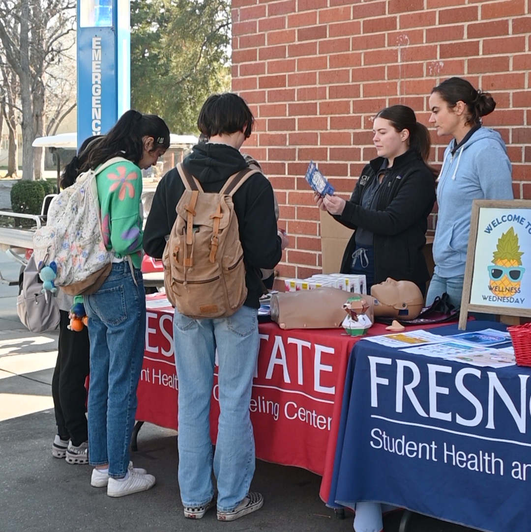 person tabling at Fresno State campus and talking to two students