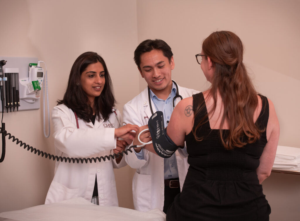 People in white coats taking blook pressure of patient sitting on bench