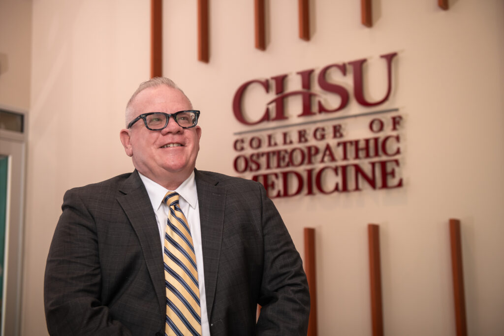 Dr Graneto in front of CHSU College of Osteopathic Medicine sign