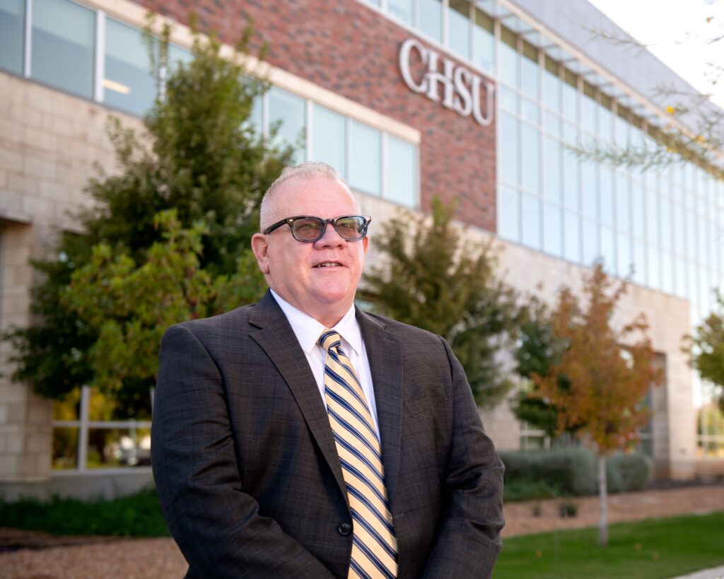 Dr. Graneto in front of building with CHSU sign