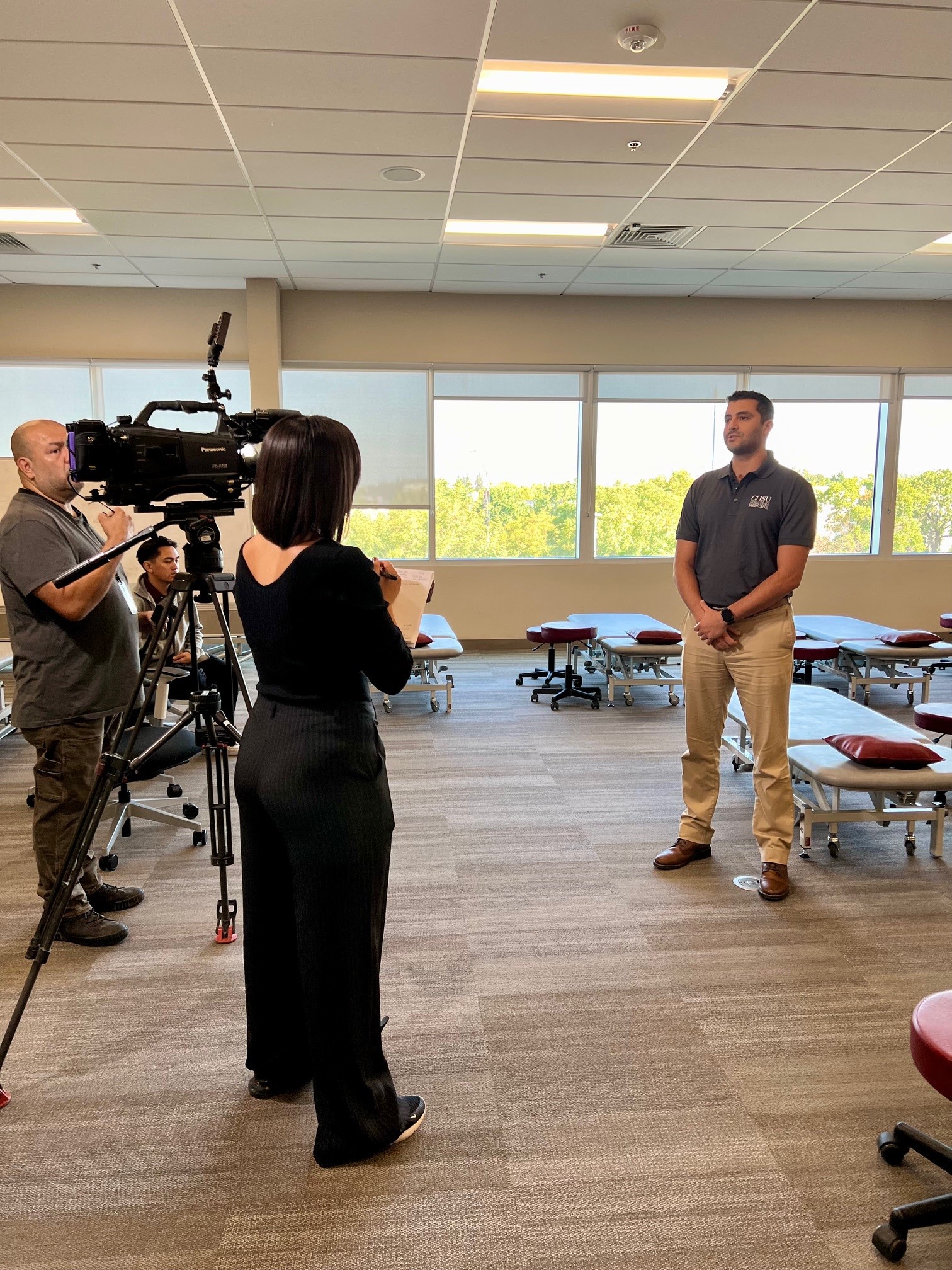 Female reporter and camera man interviewing male faculty member