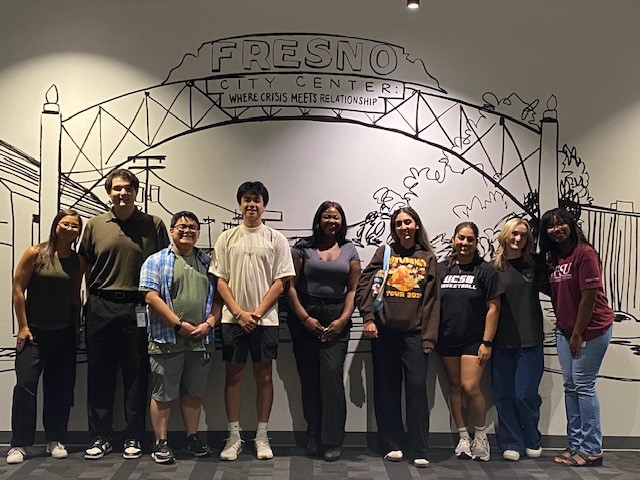 group students under painted arch on wall at Fresno Mission
