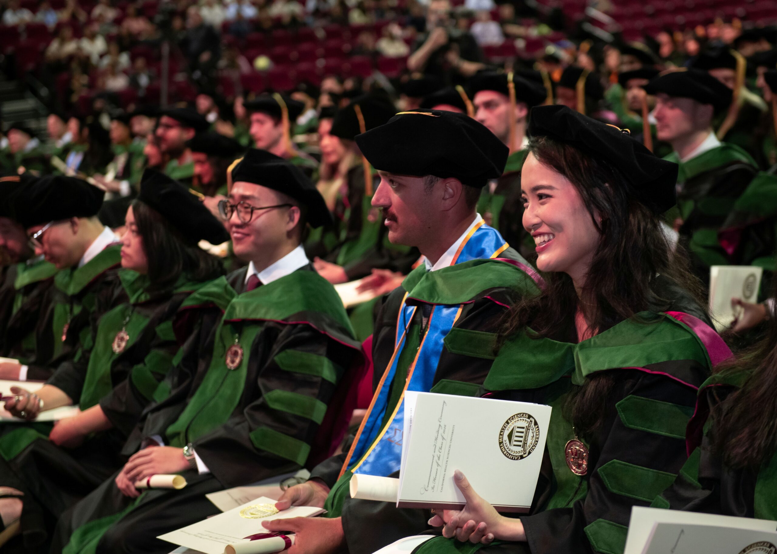 COM graduates seated wearing regalia at Commencement