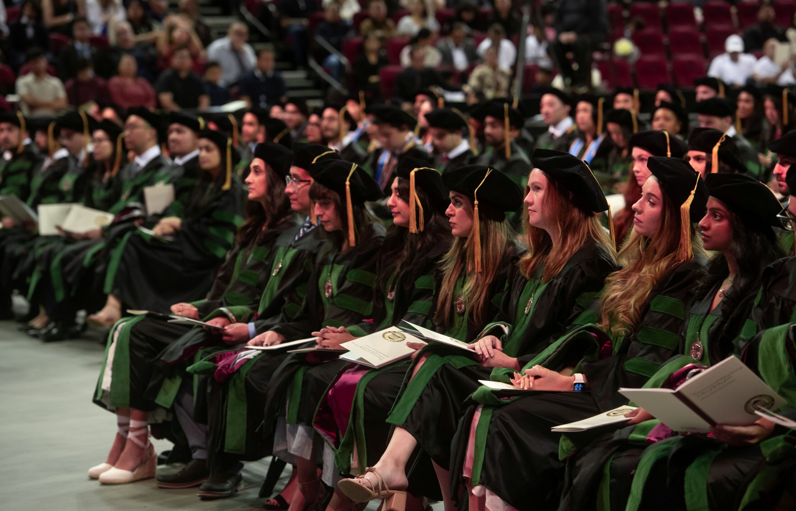 COM graduates seated wearing regalia at Commencement
