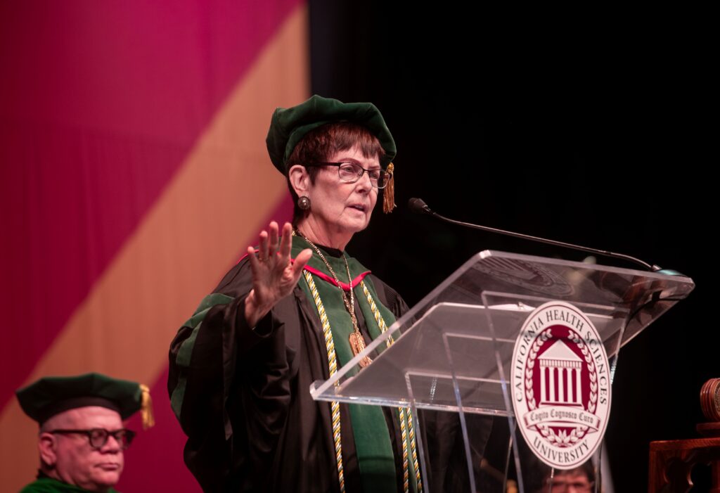 Dr Karen Nichols speaking at podium in academic regalia