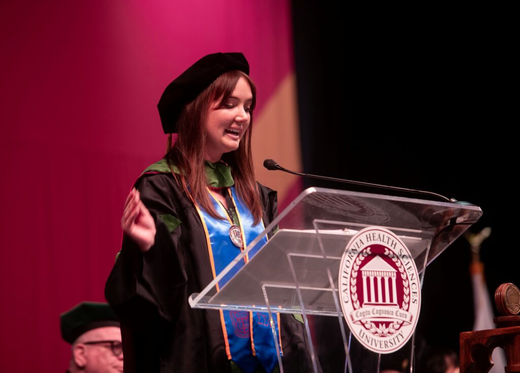 Dr Cortland Jell speaking at podium in academic regalia