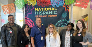 men and women standing in front of Hispanic heritage month sign