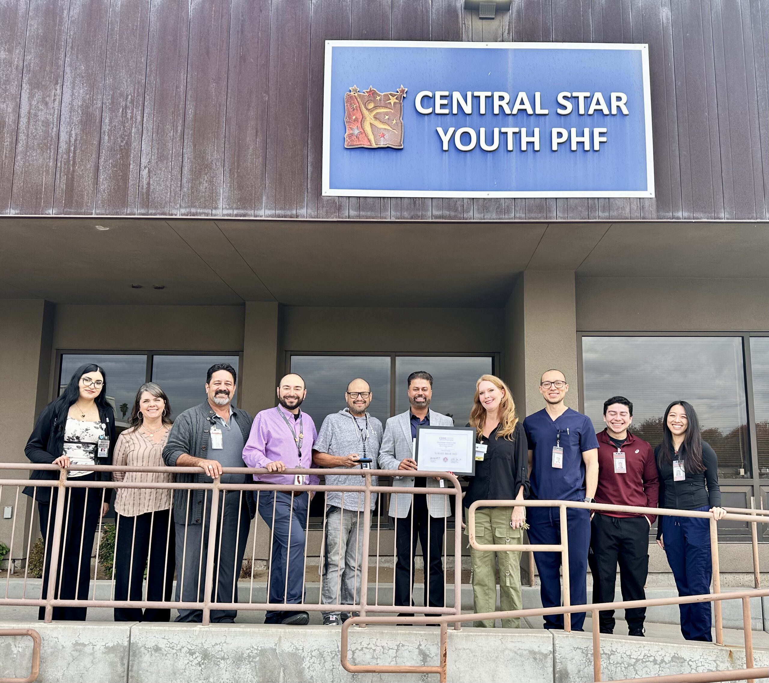 Group photo under Central STAR Youth PHF sign for presentation of Preceptor of the Year in psychiatry to Dr. Sukhjit Brar at Central Star Behavioral Health