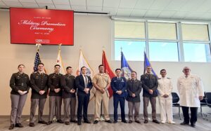 military officers graduation medical school standing in uniform in front of US military flags with Captain Bautista and Dean Graneto