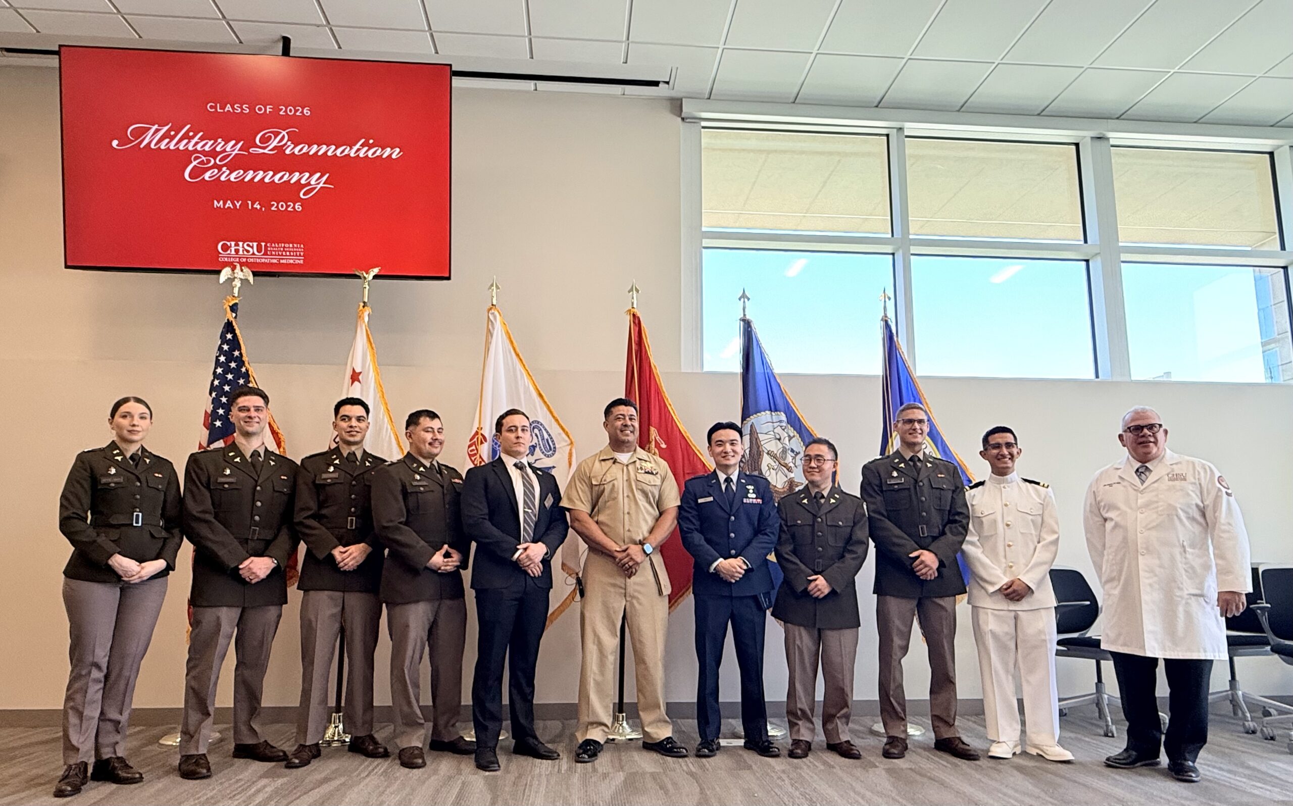 military officers graduation medical school standing in uniform in front of US military flags with Captain Bautista and Dean Graneto