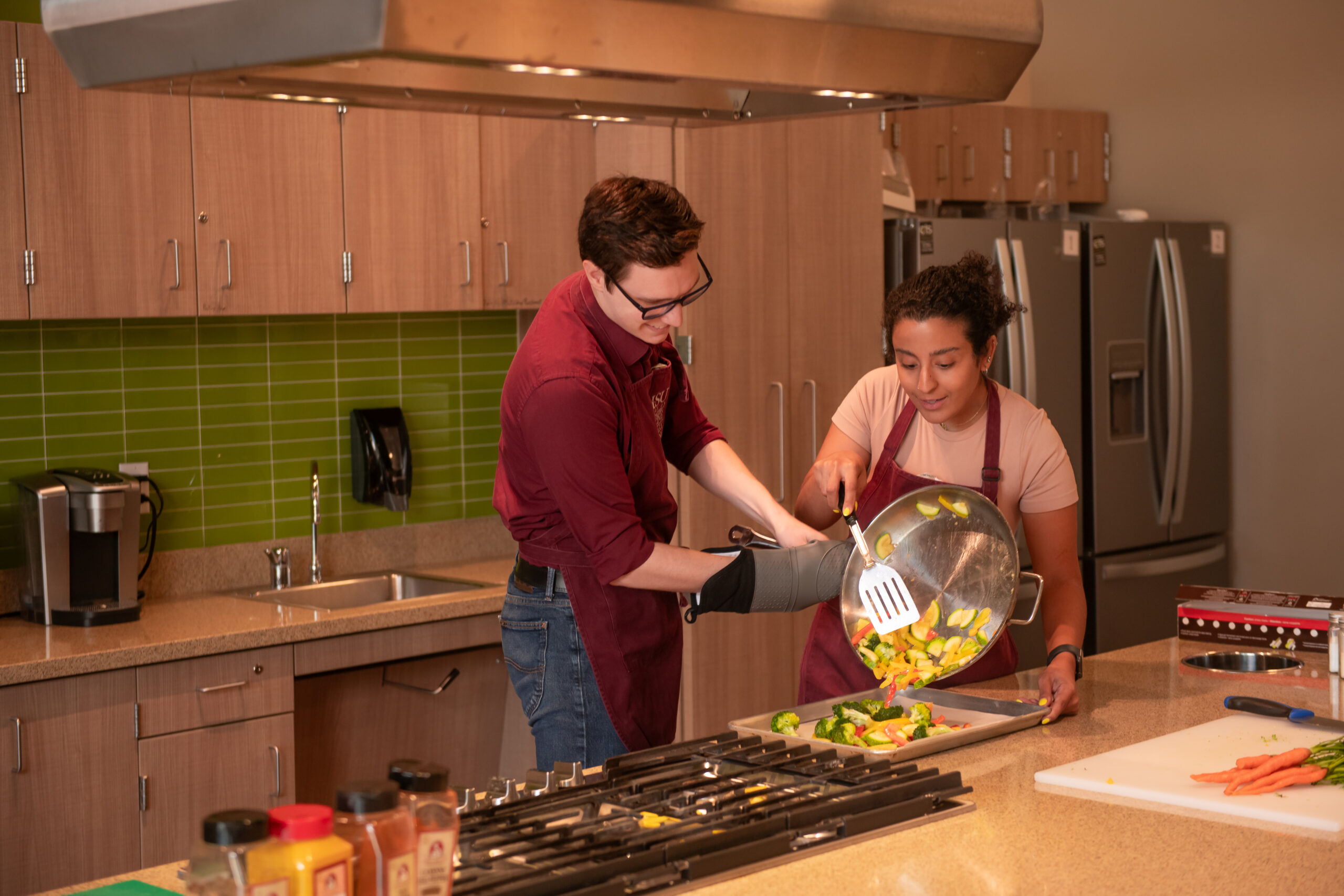 students adding food to tray from bowl