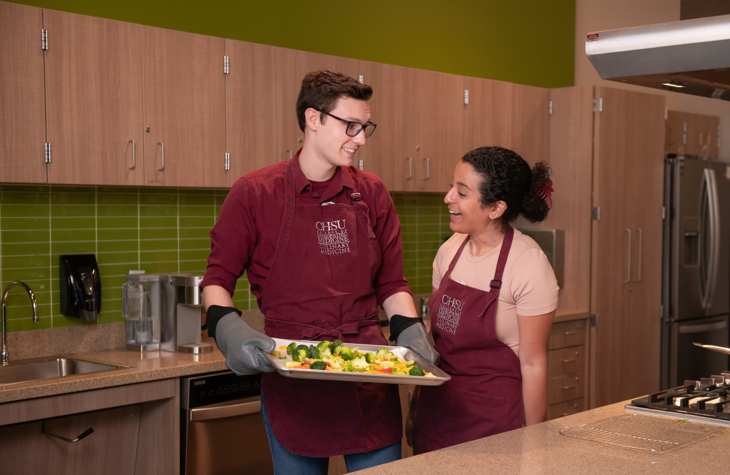 student holding cooking tray of food