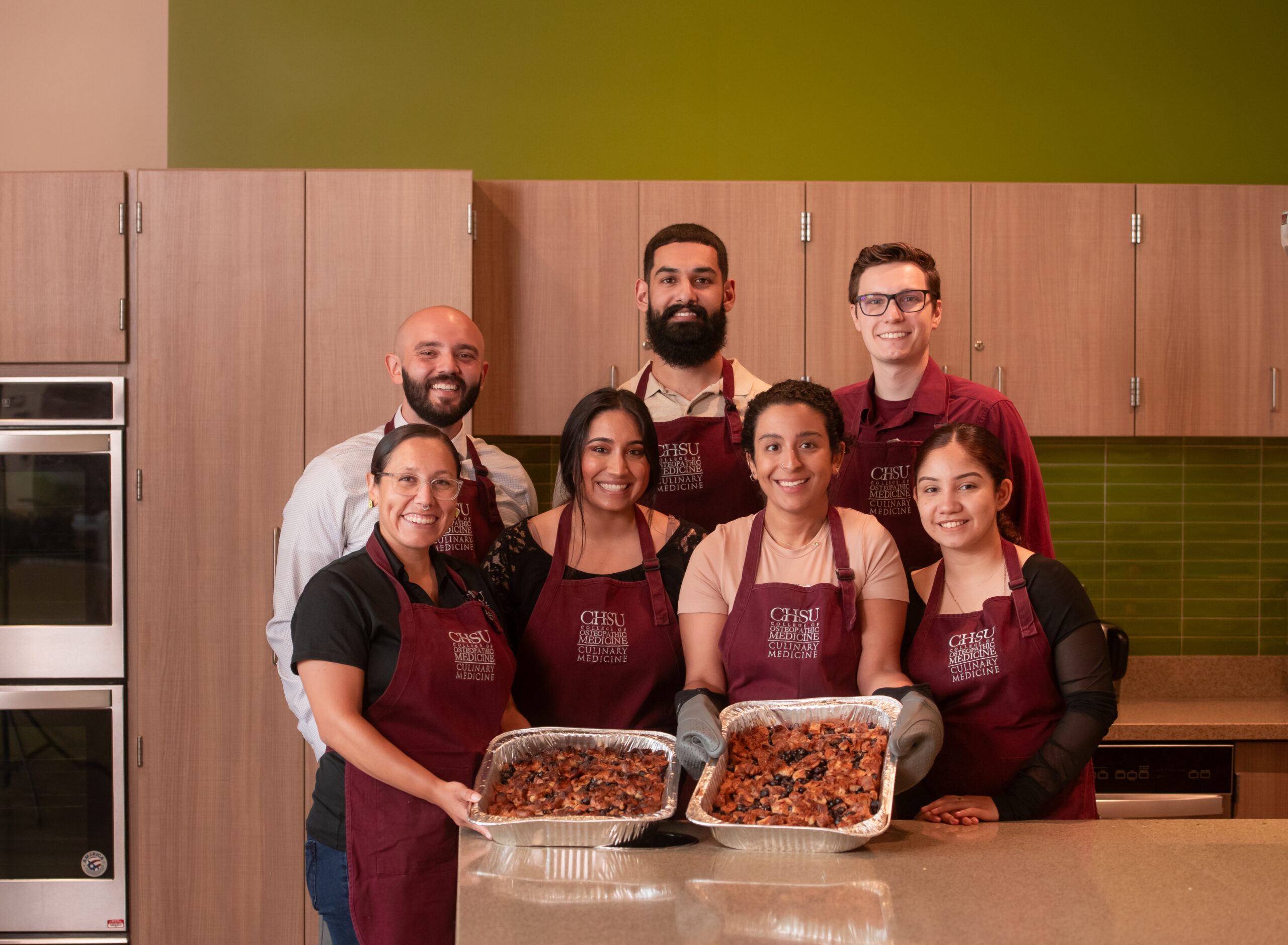 students in teaching kitchen showing cooked food in trays