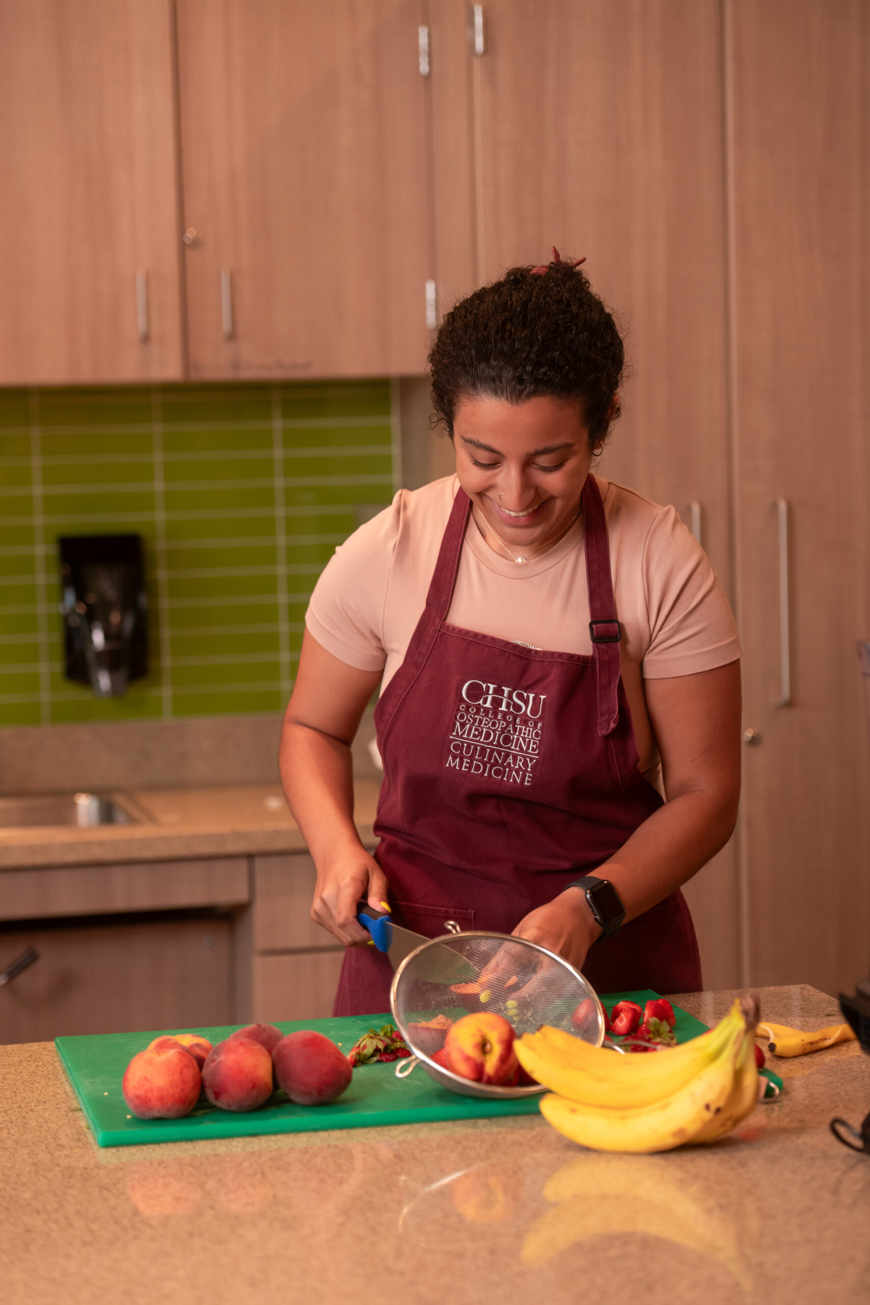 student chopping fresh fruit in teaching kitchen