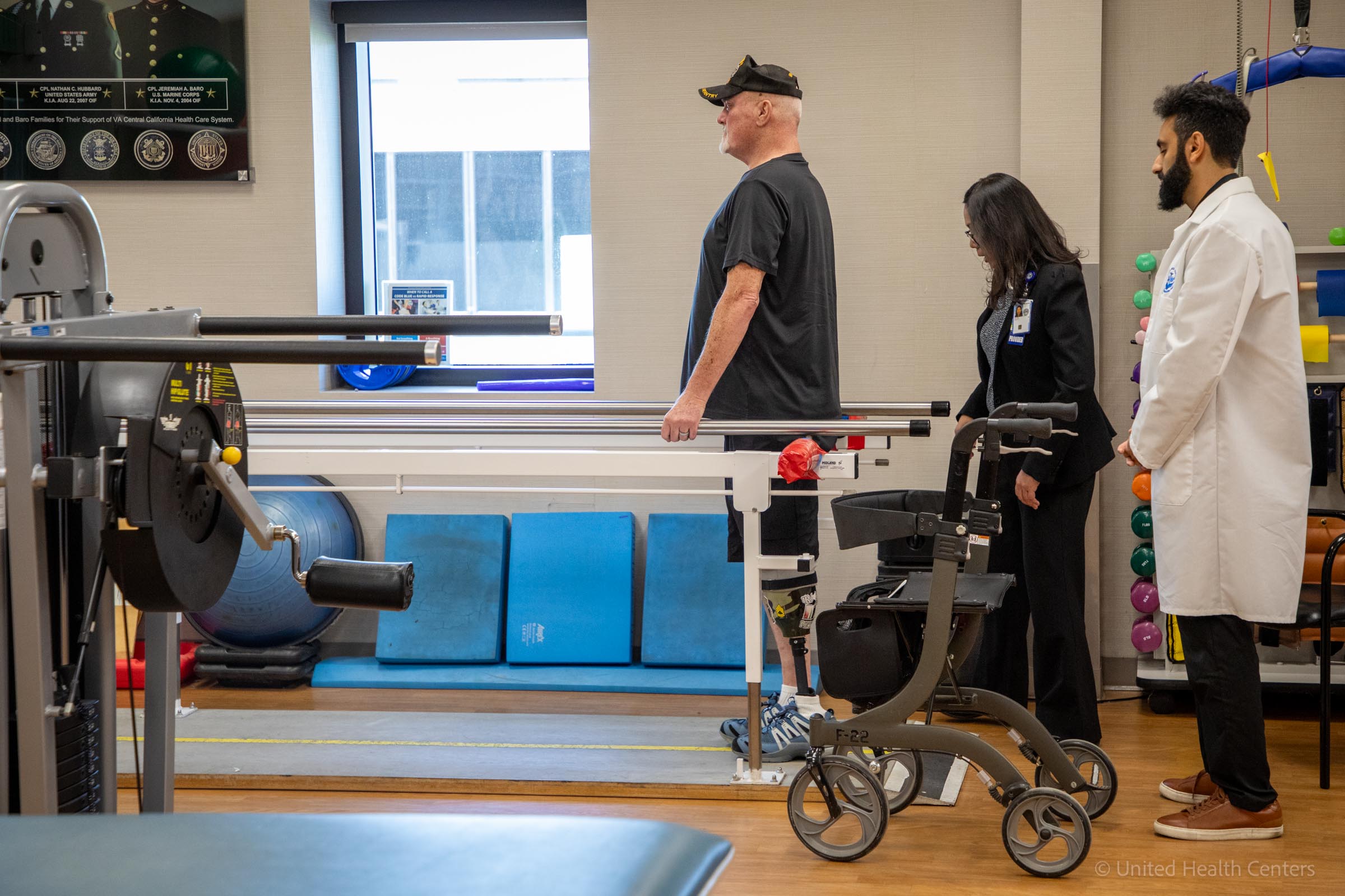 Dr. Molina and Dr. Amireh helping patient with walking holding bars