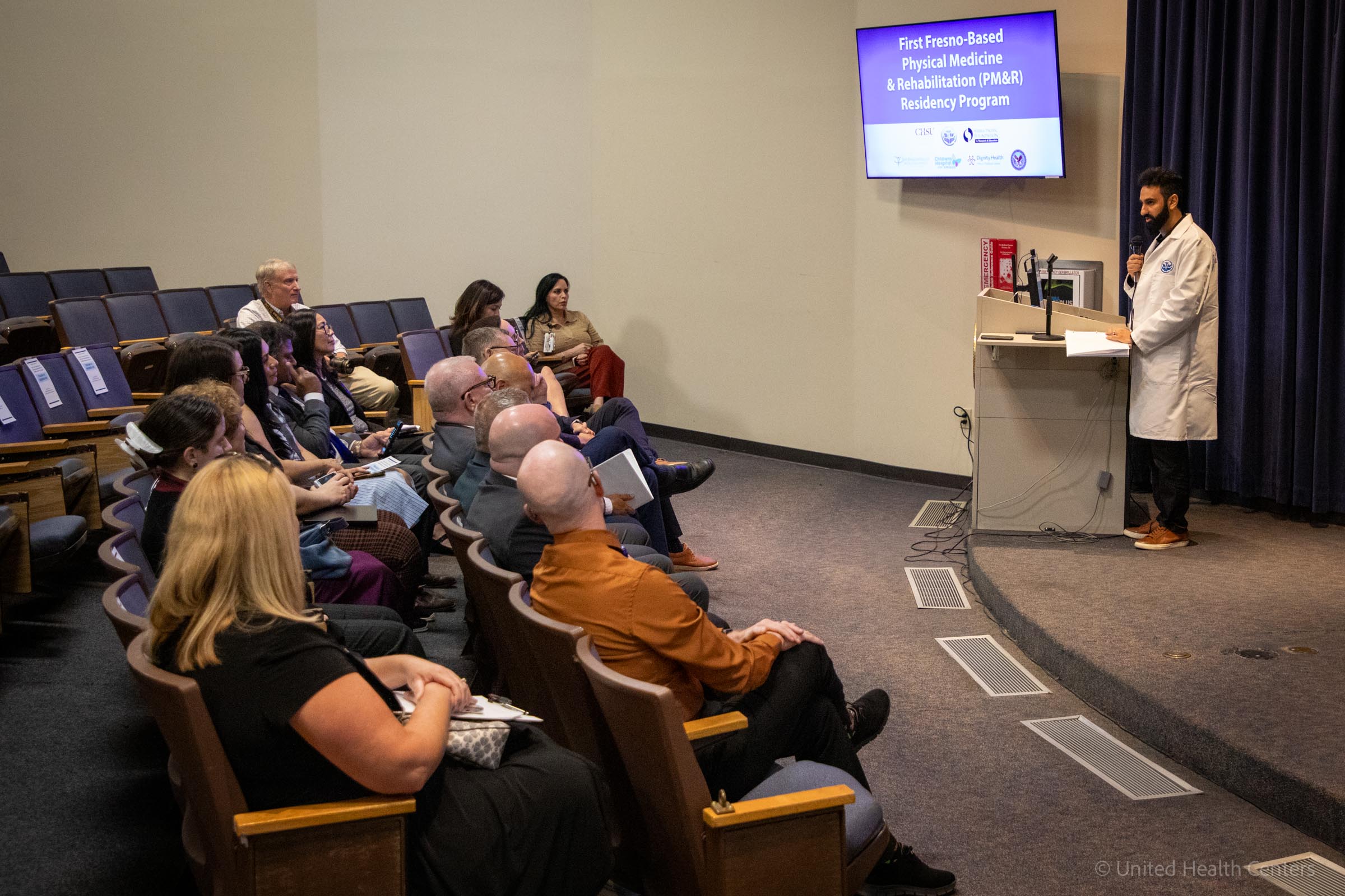 Dr. Karim Amireh speaking at Podium with screen in auditorium