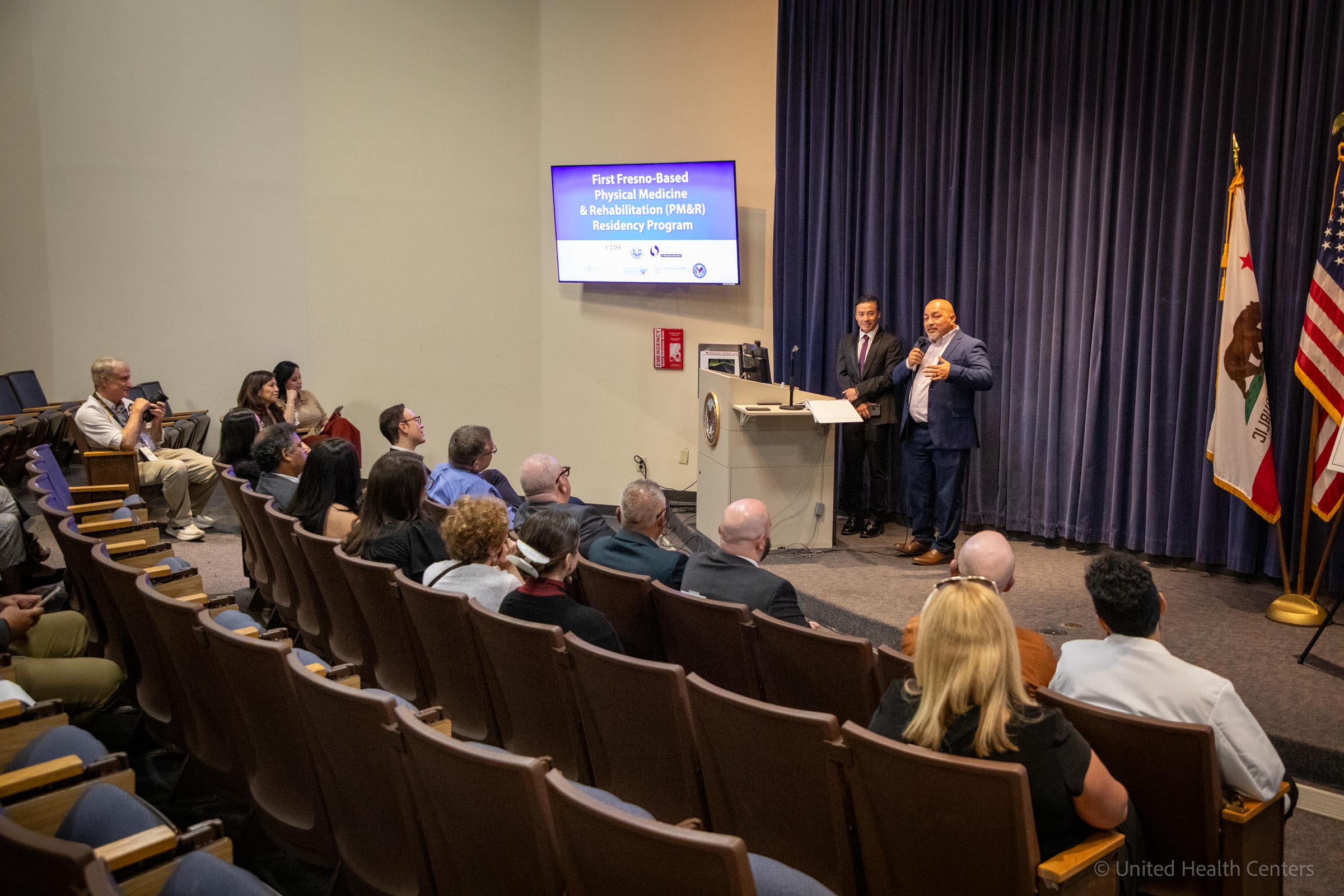 Miguel Rodriguez speaking at podium with screen in auditorium