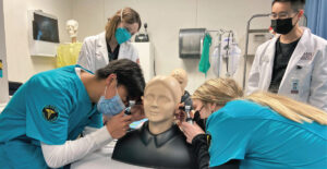 Medical students observe high school students doing ear exams.