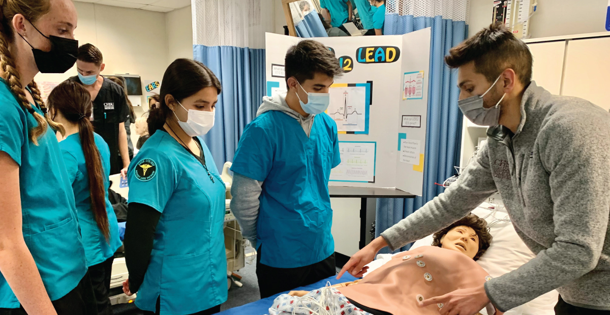 Medical student showing high school students where a heartbeat can be found on a chest.