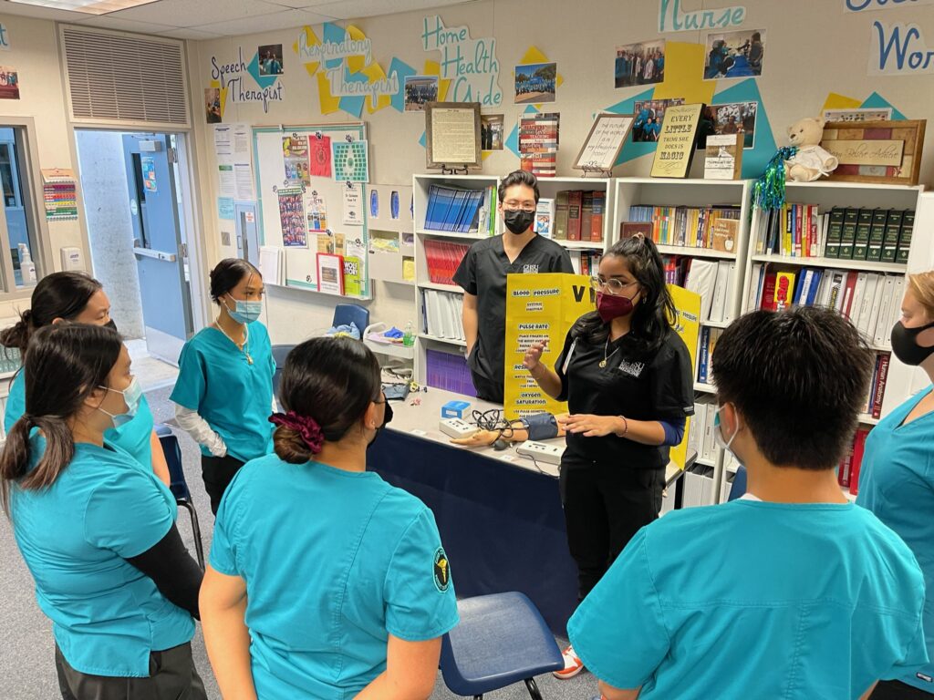 Medical student teaching high school students about how to perform medical exams.