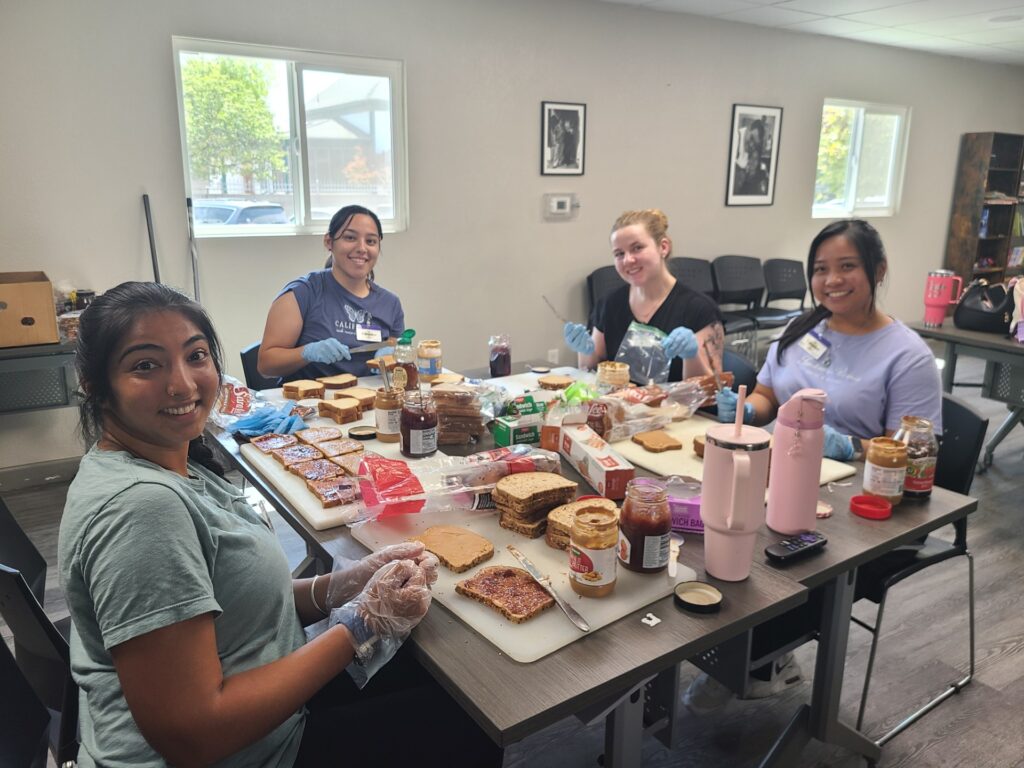 Four CHSU Valley Reach medical students wear gloves while making peanut butter and jelly sandwiches for guests at Poverello House in Fresno.