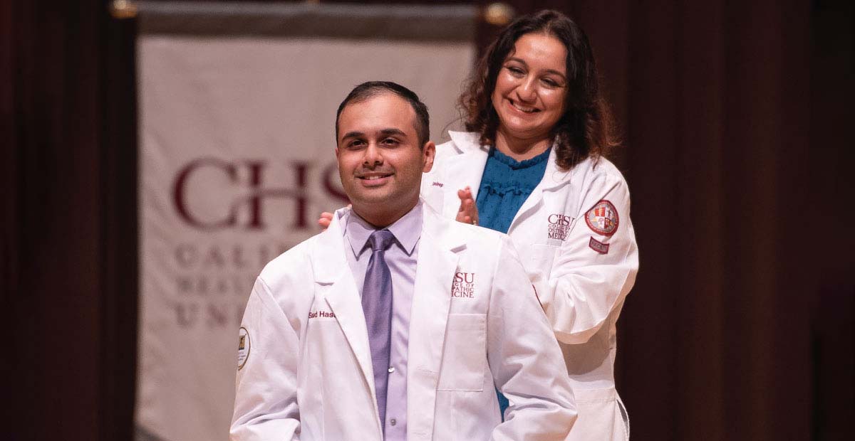 Man receiving white coat during ceremony