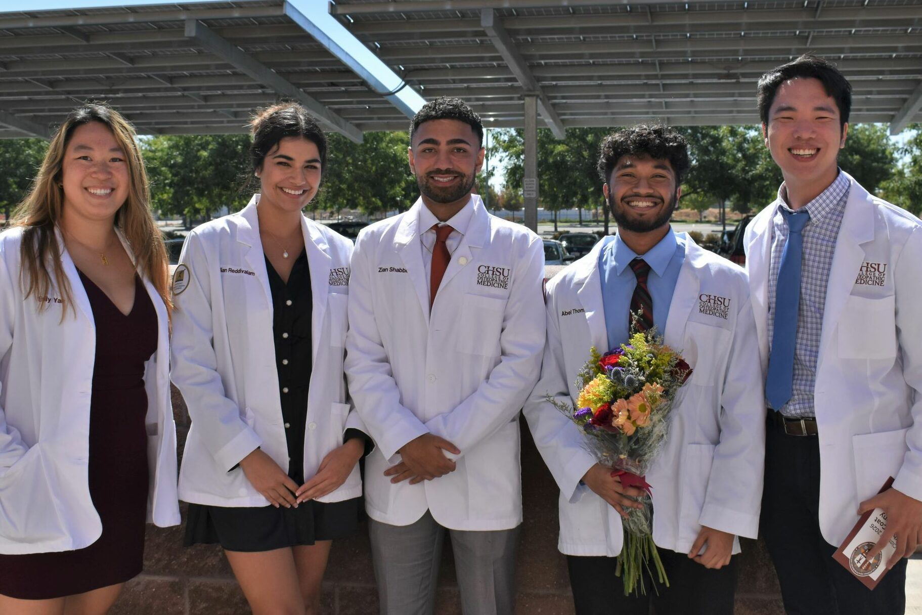 Students in white coats posing for camera